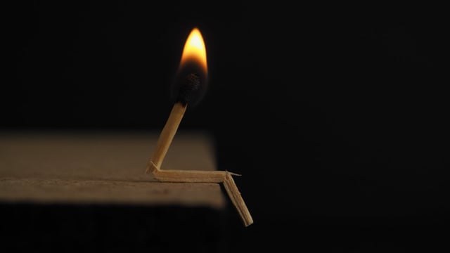 A broken matchstick with a burning flame, symbolizing burnout and fragility.