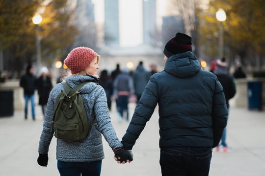 Couple holding hands and walking together along a city street.