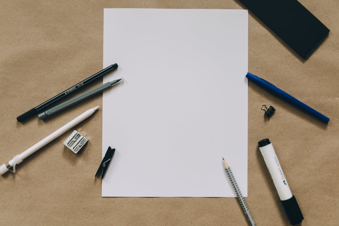 A blank piece of paper surrounded by stationery.