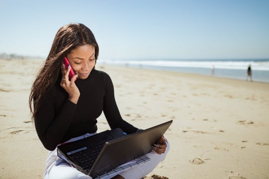 A digital nomad working on their laptop while relaxing on a scenic beach, embodying the flexibility and freedom of the lifestyle.